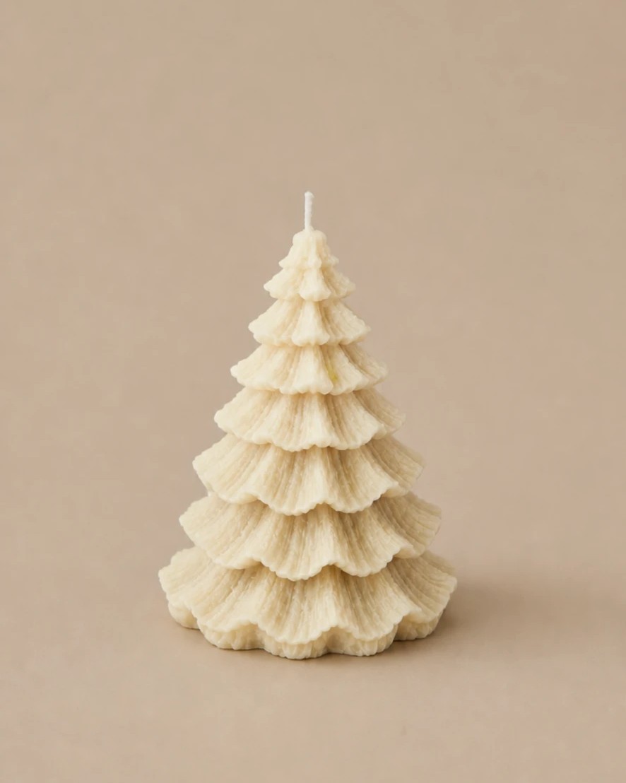 The Pine, an ivory soy wax layered pine tree candle, on a warm beige backdrop